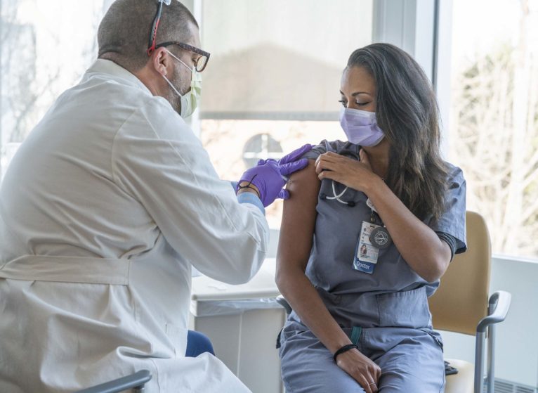 Ebony Hilton, MD, receives the first COVID-19 vaccine administered at UVA Health.