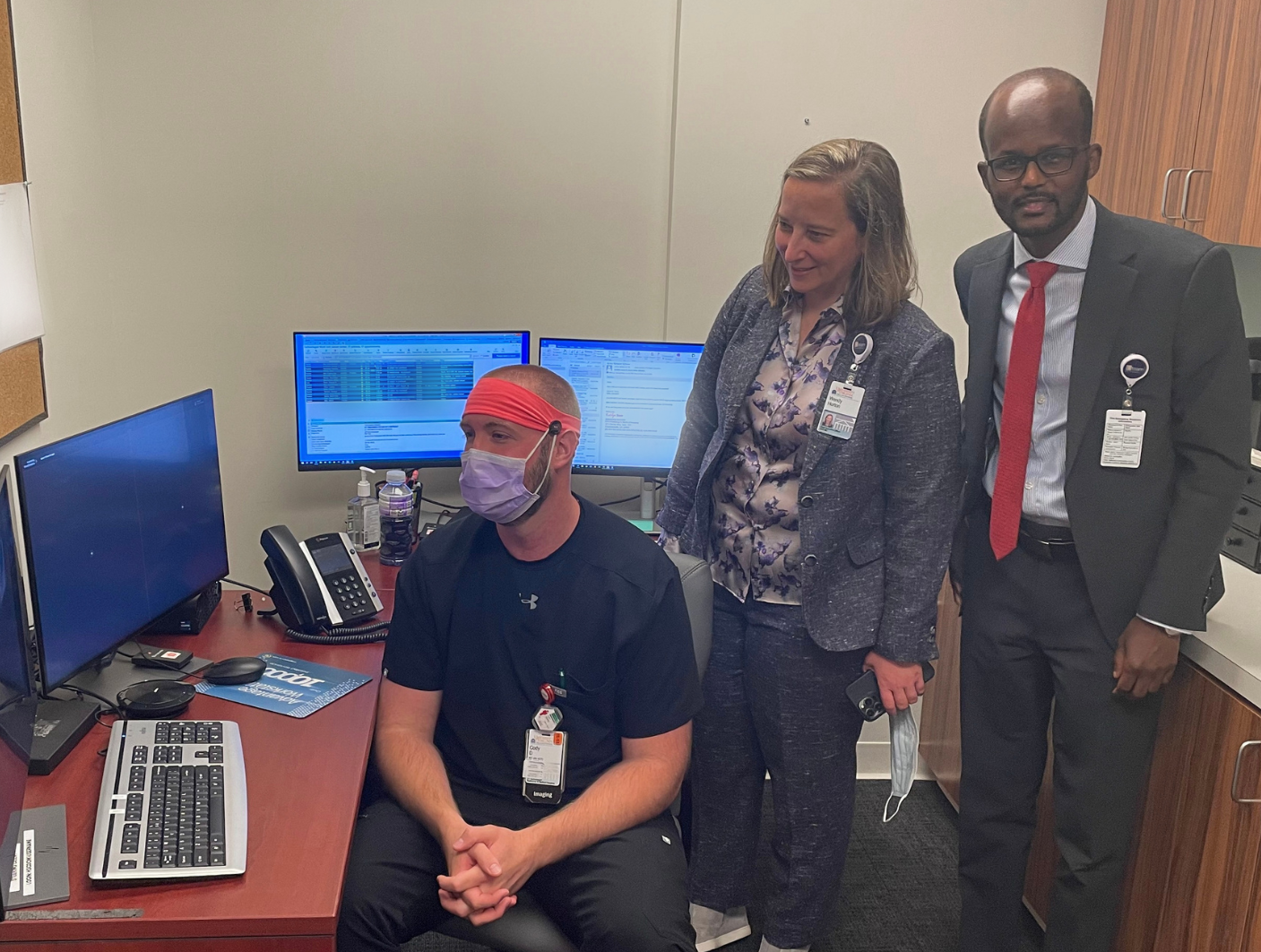 Cody Desper, Lead Computed Tomography (CT) Technologist, shows Wendy Horton and Abdi Somo, Chief Administrative Officer syngo Virtual Cockpit