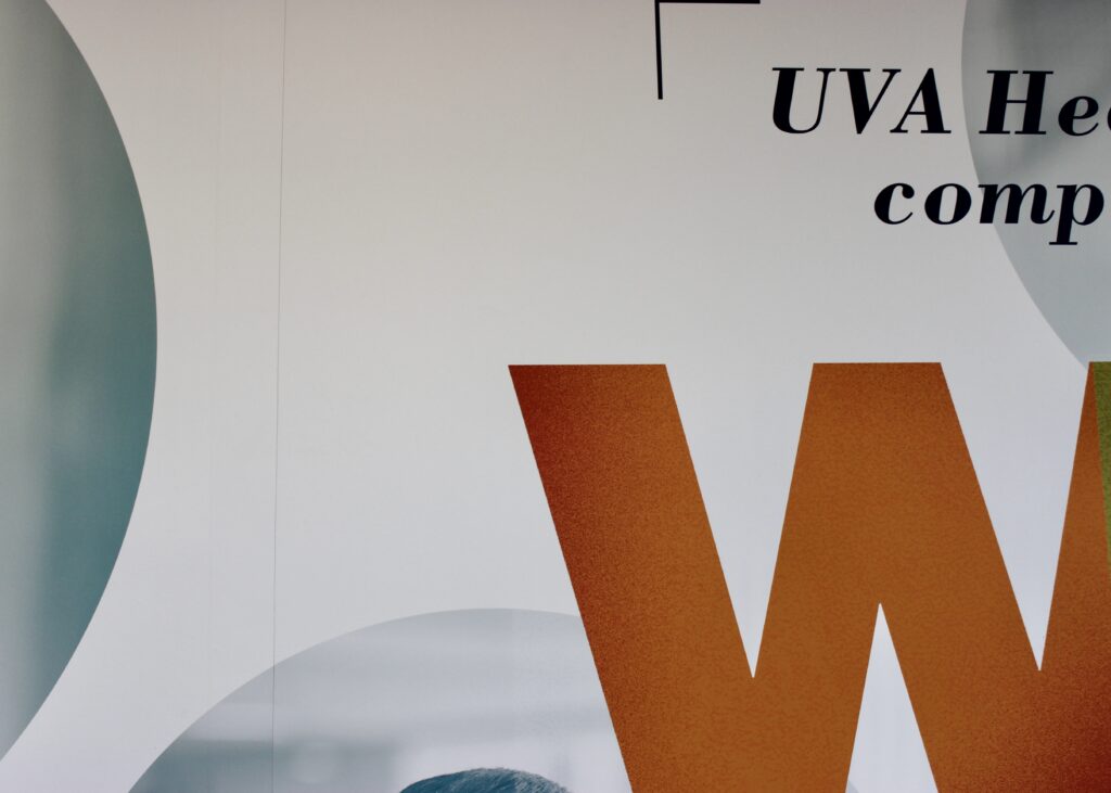 Close-up photo of sign:
"UVA Hea-"
"comp-"
"W"